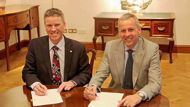 Ricardo CEO Dave Shemmans and Lloyd's Register CEO Richard Sadler sitting at a table smiling signing the Purchase Agreement