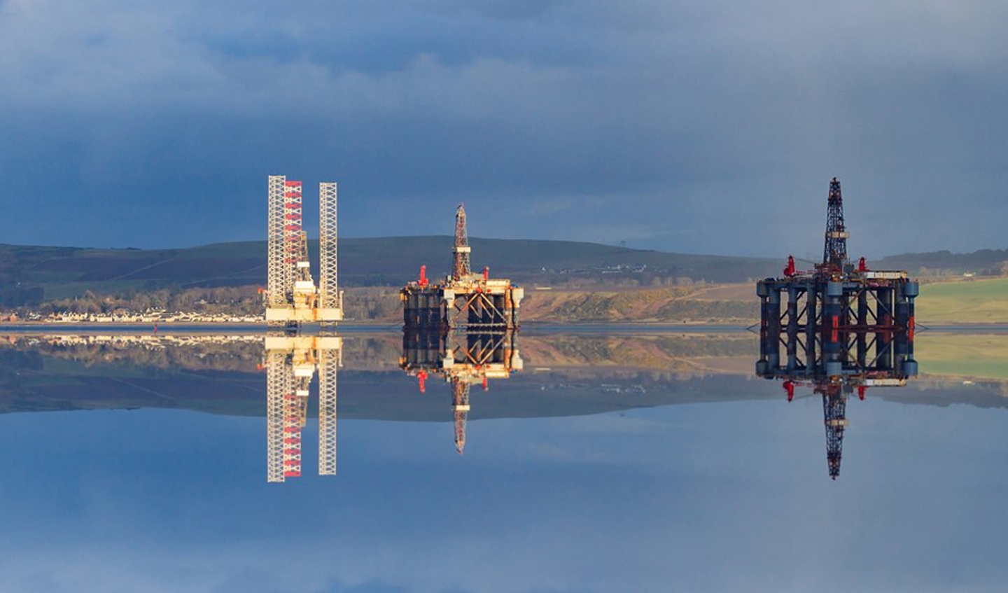A semi-submersible oil-rig with a rainbow and sandy shores. 