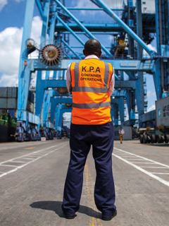 An African surveyor stands at a docking container site. 