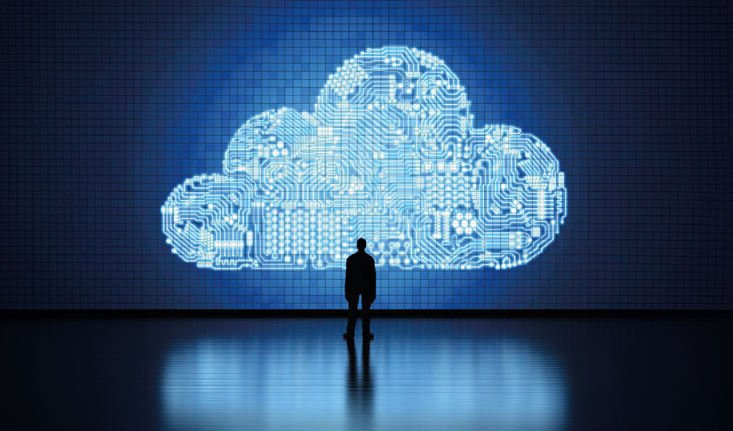A man stands in front of a large digital cloud icon.