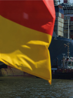A german flag and a container ship in the background. 