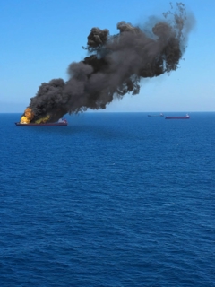 A cargo ship on fire out at sea.
