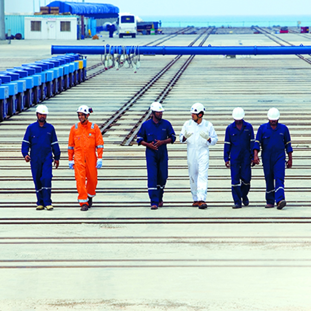 Offshore engineers in different coloured safety coveralls walking
