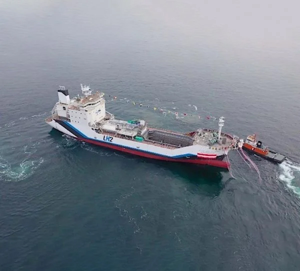 Top side view of Suiso Frontier ship on launch day with tug boat at its side.