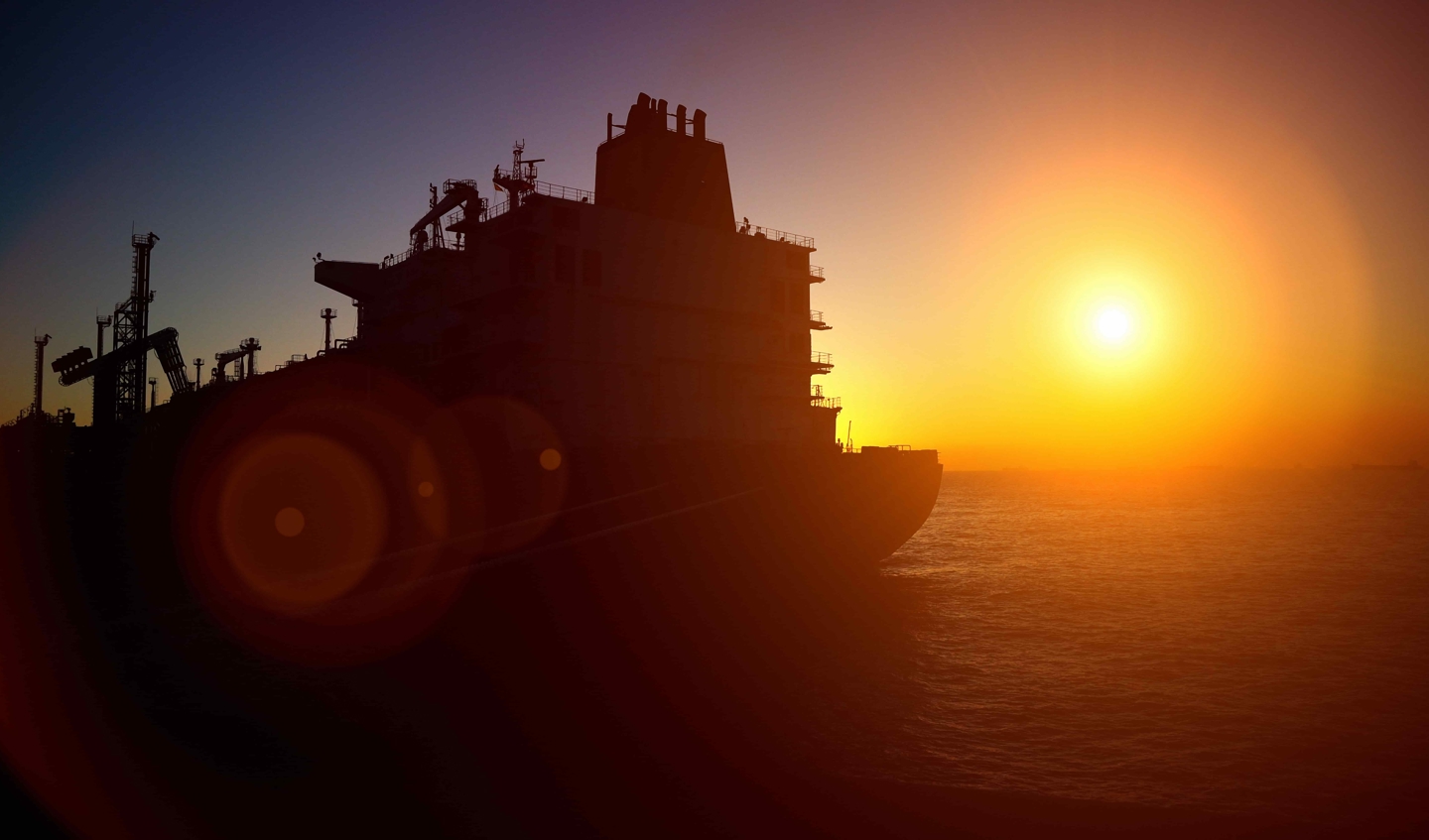 Offshore rig backlit by sunset.