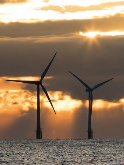 Offshore wind farm with a sunset backdrop.