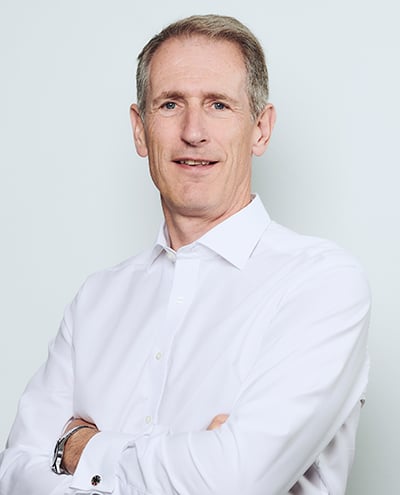 A photo of Alastair Marsh with his arms crossed in a white shirt