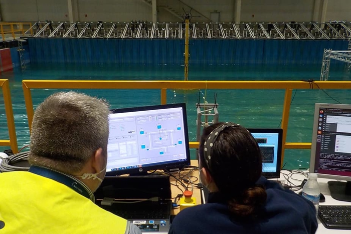 Two workers sit at a desk to perform a tank test of the active ballast control system.