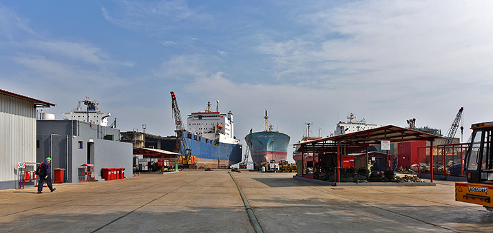 Two ships docked near a factory