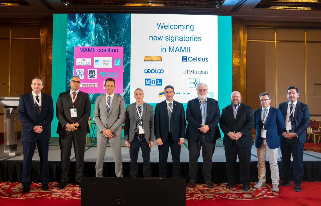 Group photo of members and signatories in front of signage that reads Welcoming new signatories in MAMII