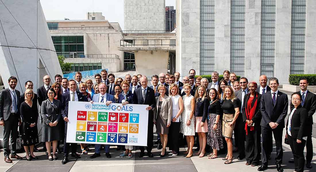 Large group of UN members and LR members outside of building holding sustainable development goals sign