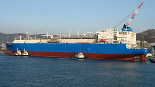 Side view of one of the 155,000 cbm (cubic metres) ships win the water with three tug boats next to it. 
