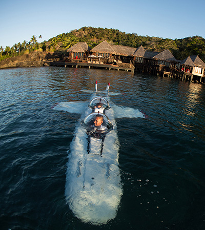 Front view of personal submarine in operation surfacing from the water with crew member visible in window