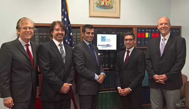 Group photo of Lloyd's Register and MCFO staff standing in front of book cabinet and small sign that has LR and MCFO logos.