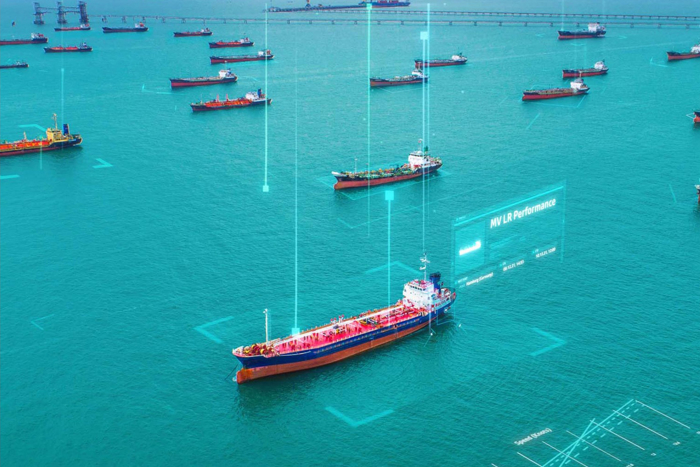 Birds eye view of ships anchored in calm seas. A digital overlay implies the central ship is selected in a user interface, and has the Ship name of MV LR Performance.