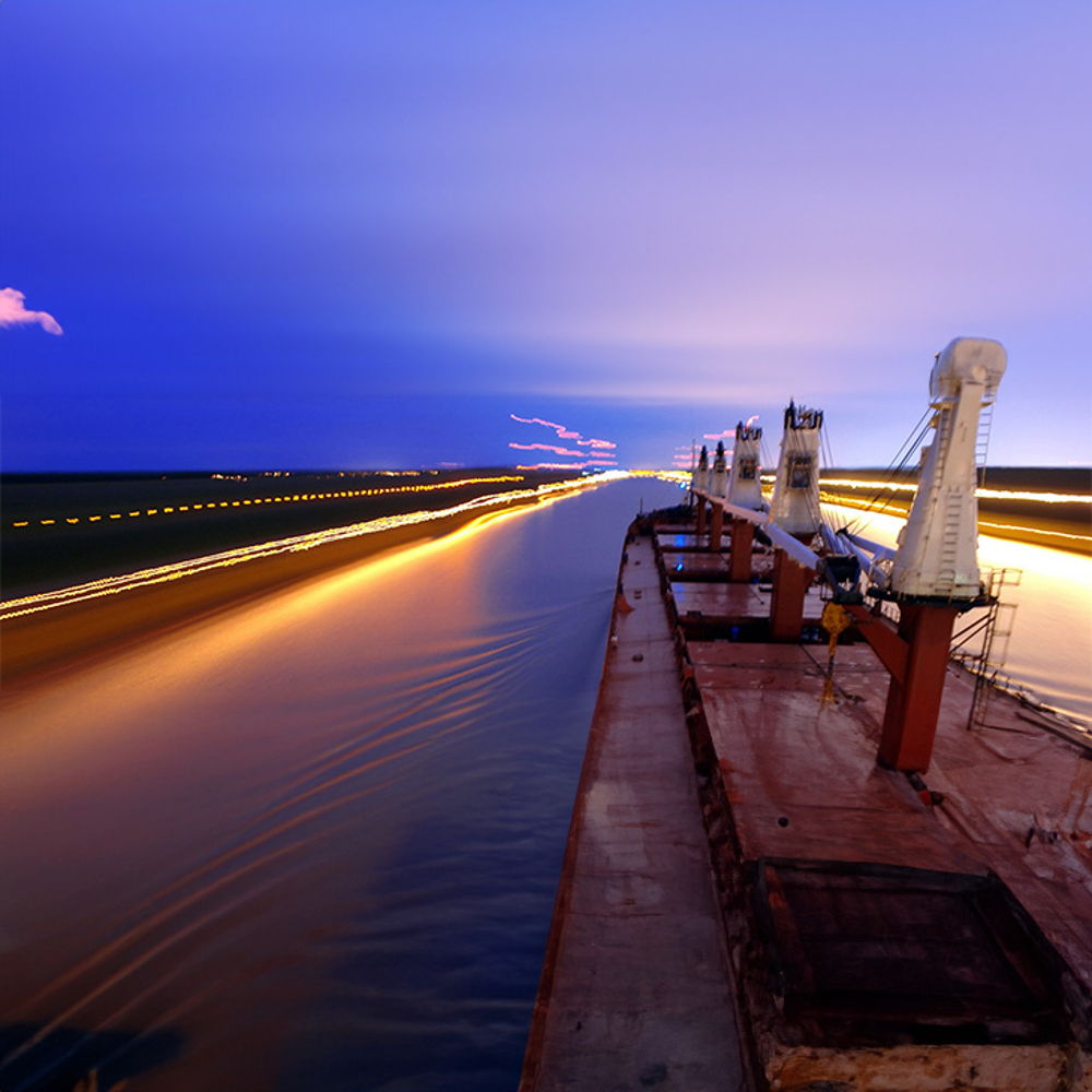 Bunker charging through night sea, lights blur.