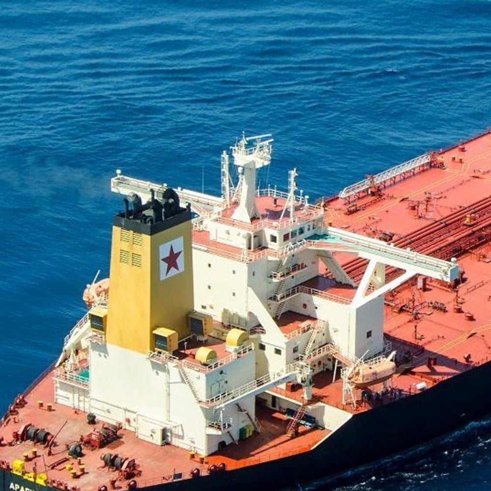 Tanker sailing in ocean with a red star logo in a white square on its yellow tower.