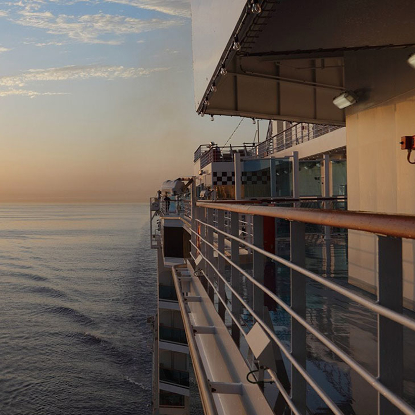 View of the ocean from the side of a passenger ship at sunset.