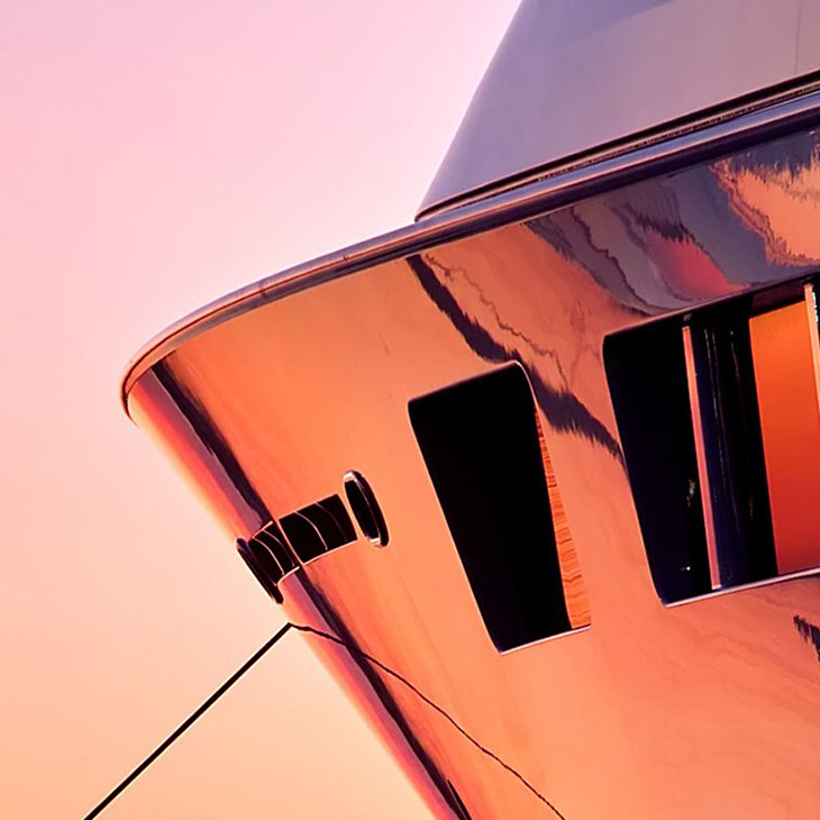 The bow of a yacht coloured by pink and gold sunset light.