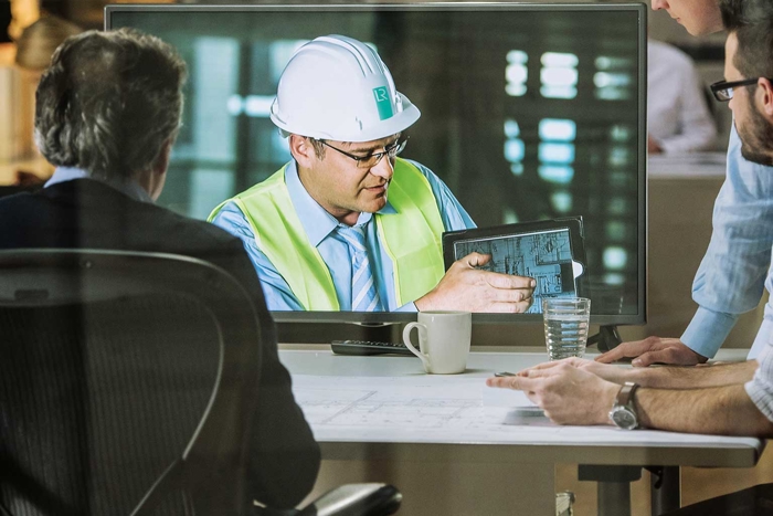 Office workers watching the video of LR engineer working on a TV screen
