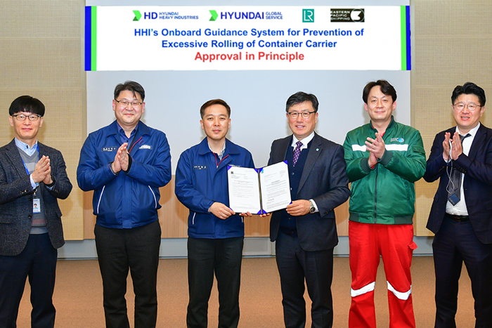 Group photo of LR and HHI representatives clapping hands and two members holding framed Approval in Principle document.