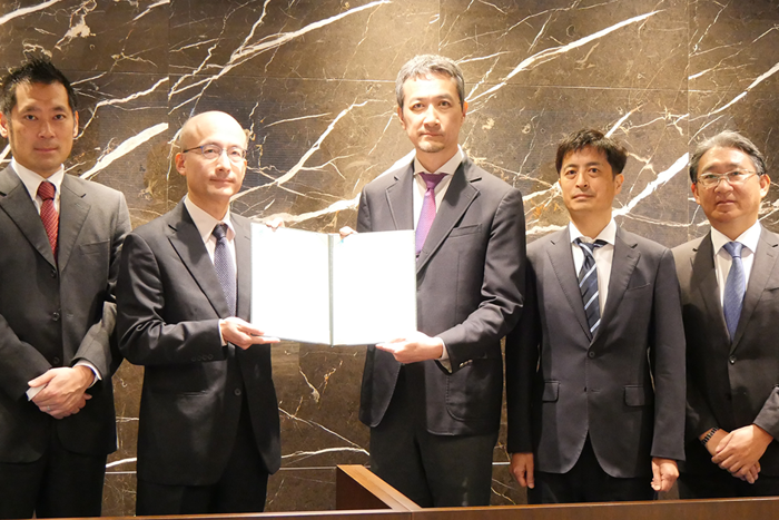 Group photo of representatives from LR and Mitsui and TSUNEISHI holding awarded Approval in Principle framed document.