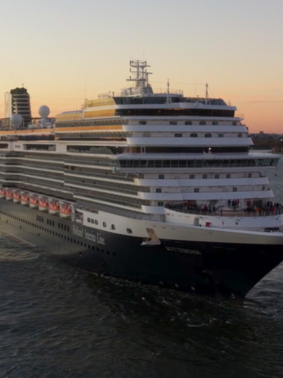 View of Holland America Line's newest Rotterdam cruise liner in New York with the Statue of Liberty in the background.