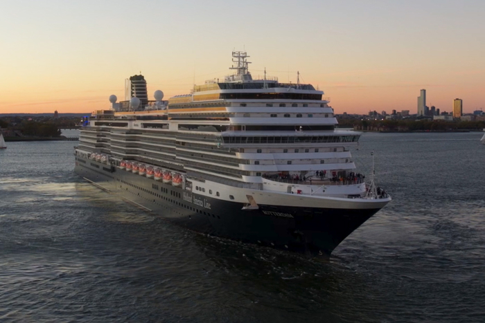 View of Holland America Line's newest Rotterdam cruise liner in New York with the Statue of Liberty in the background.