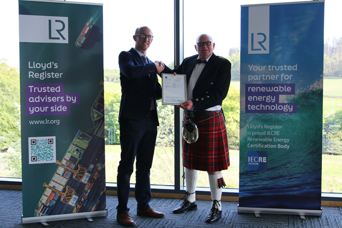 Recipient being awarded the Feasibility Statement by LR, shaking hands, with LR signage banners either side of them.